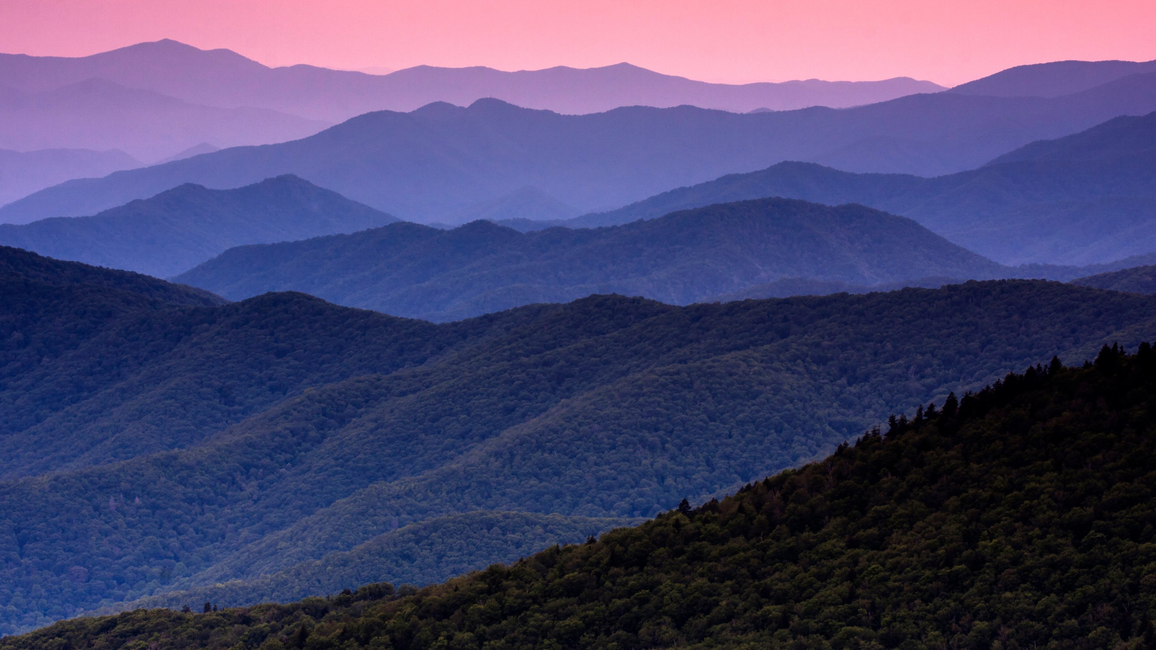 Layered Appalachian mountain ridges fading from forest green into blue-violet and rose-pink sky at dusk